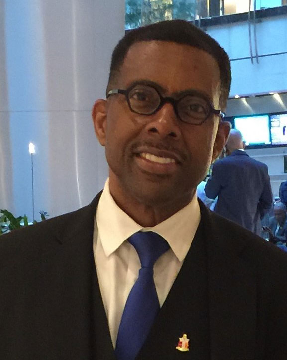 A man in a suit and tie standing next to a building.