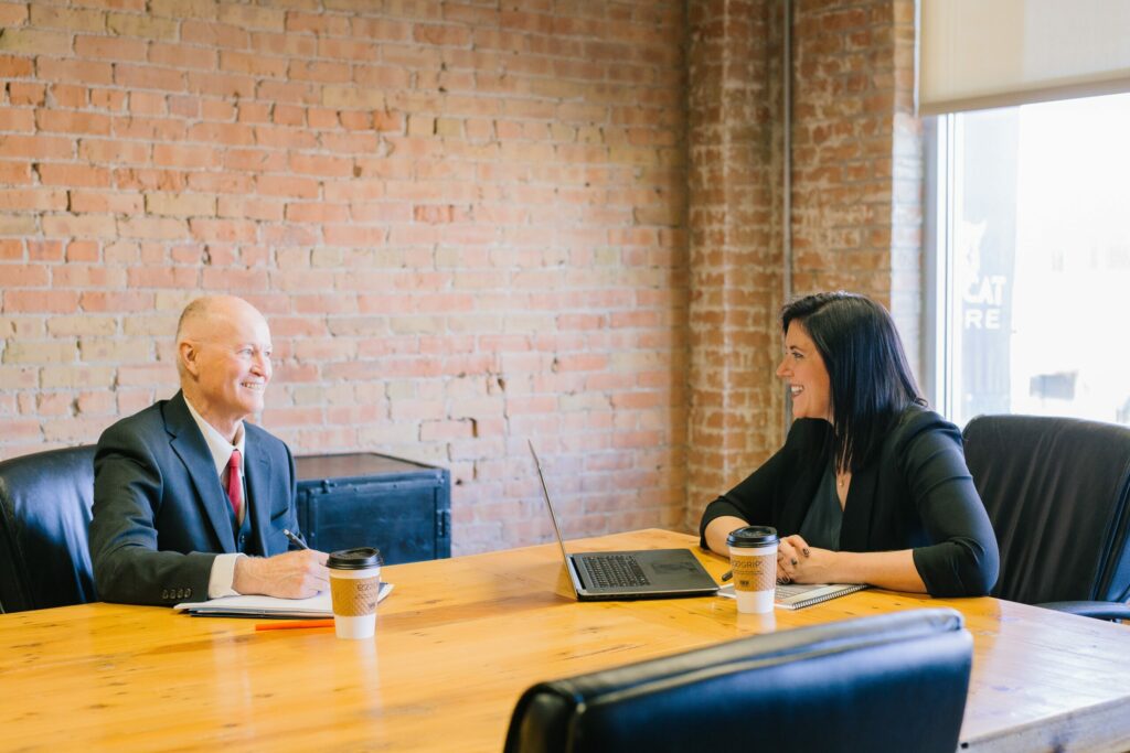 Two people sitting at a table with laptops