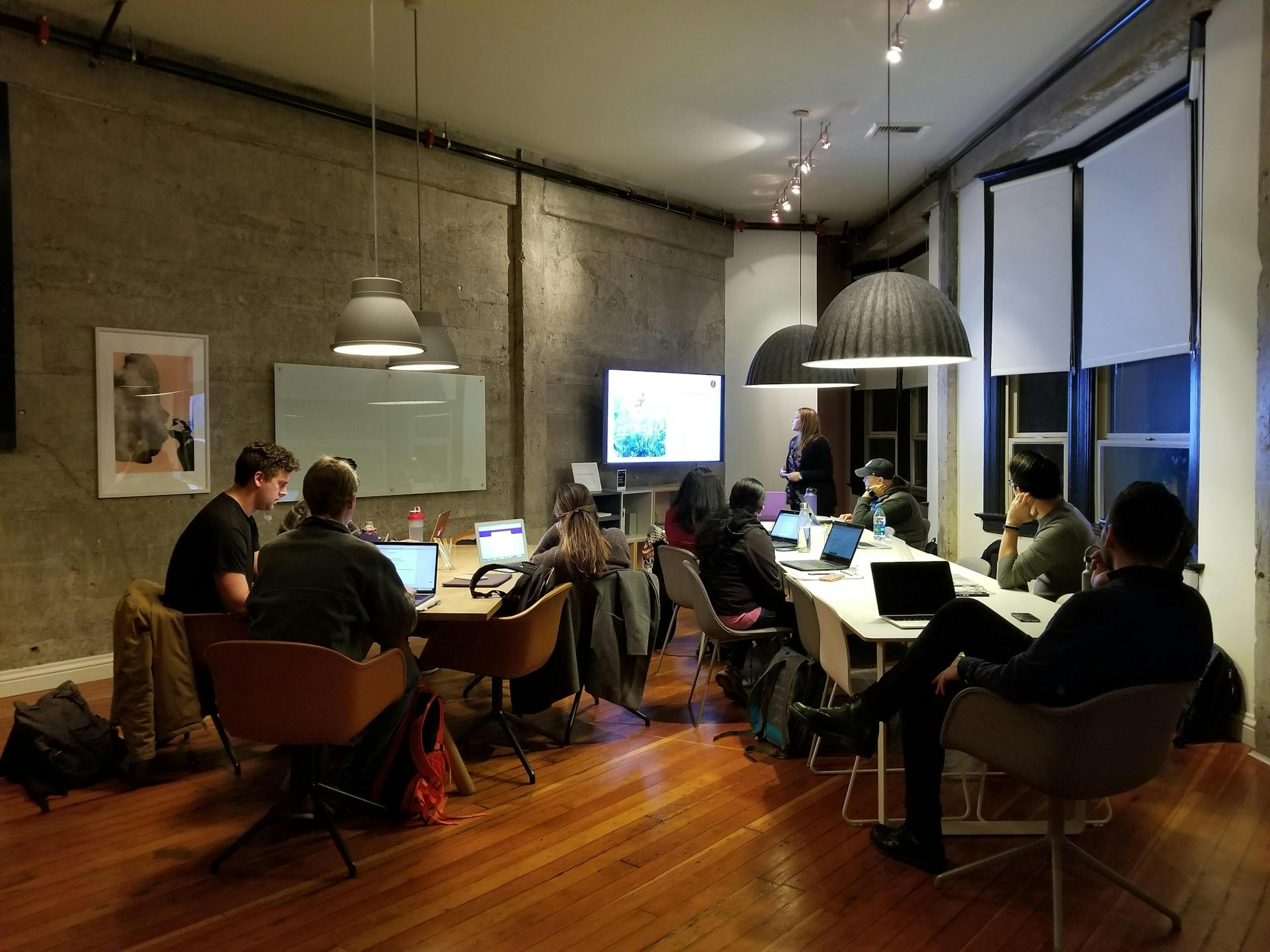 A group of people sitting around tables with laptops.