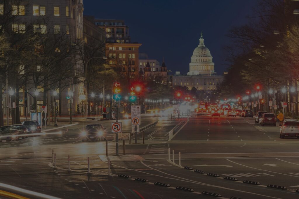 A city street with lights and buildings in the background.